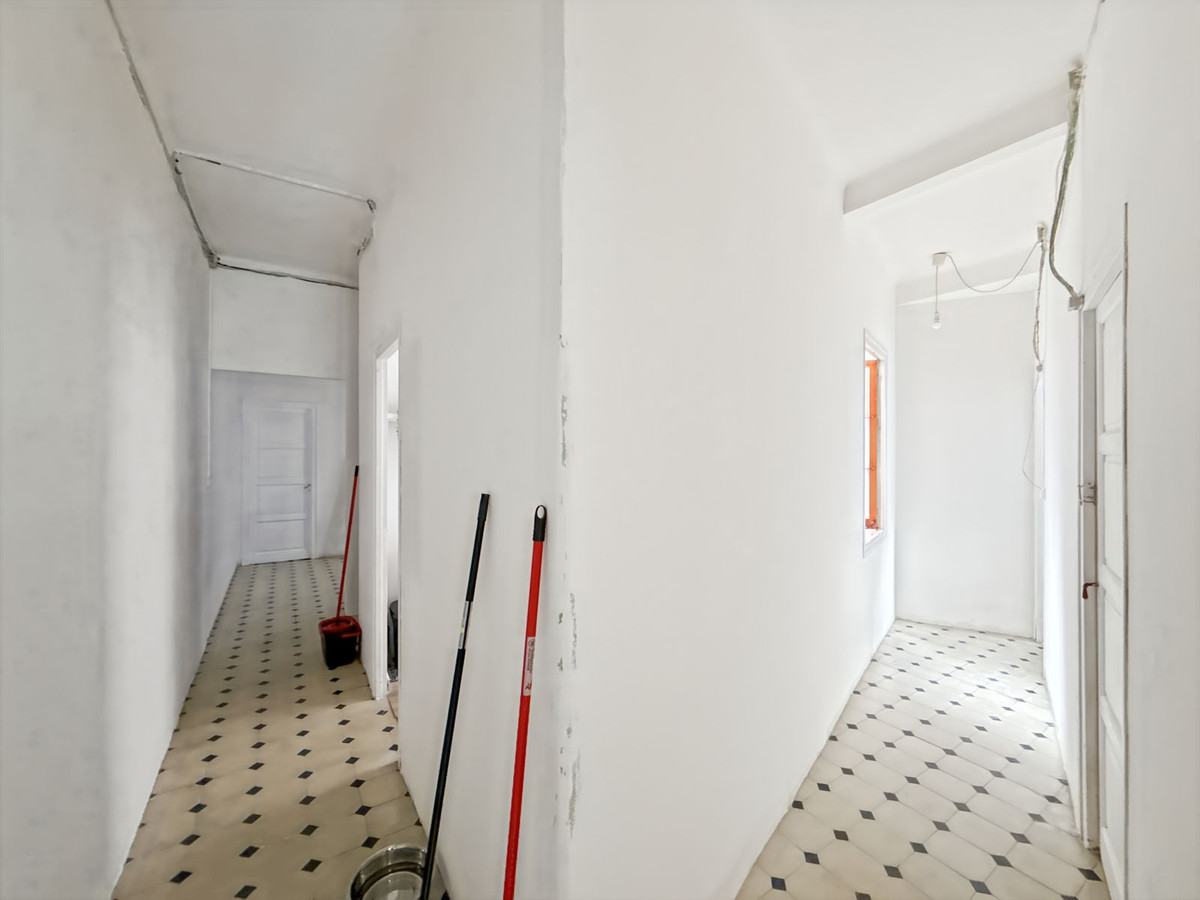 Witte renovatiehal met tegelvloer en schoonmaakspullen.