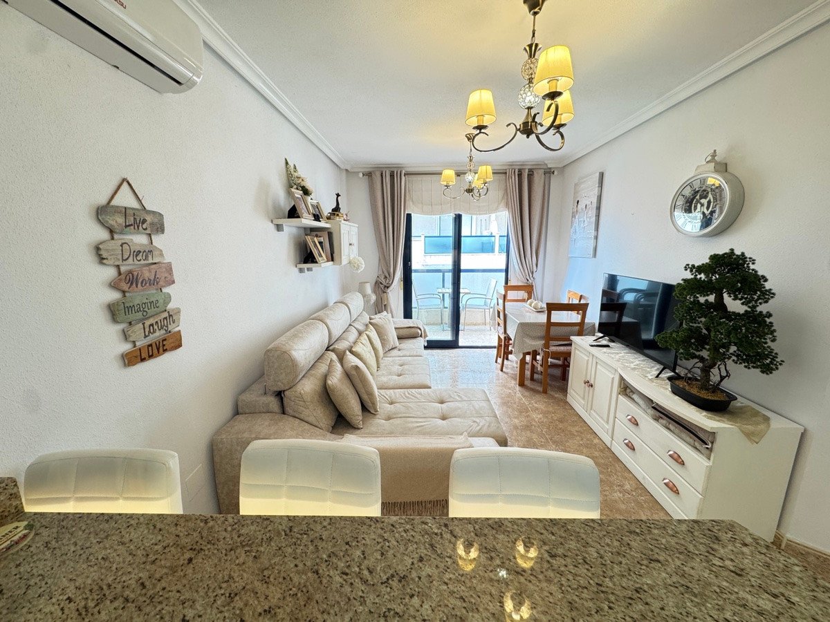 Spacious living room with a large sectional sofa, dining area, television, and access to a balcony with outdoor seating.