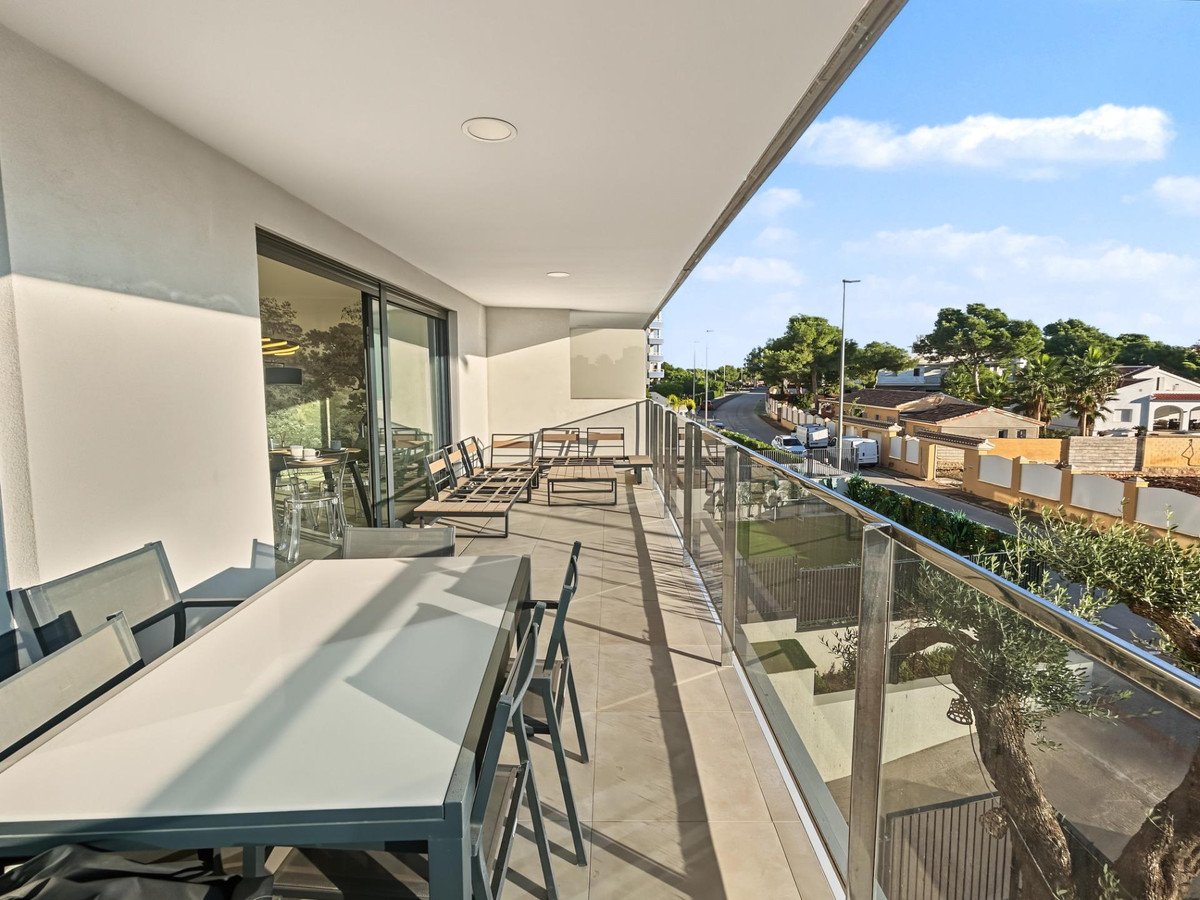 Modern balcony with glass railing, outdoor dining, and lounge furniture