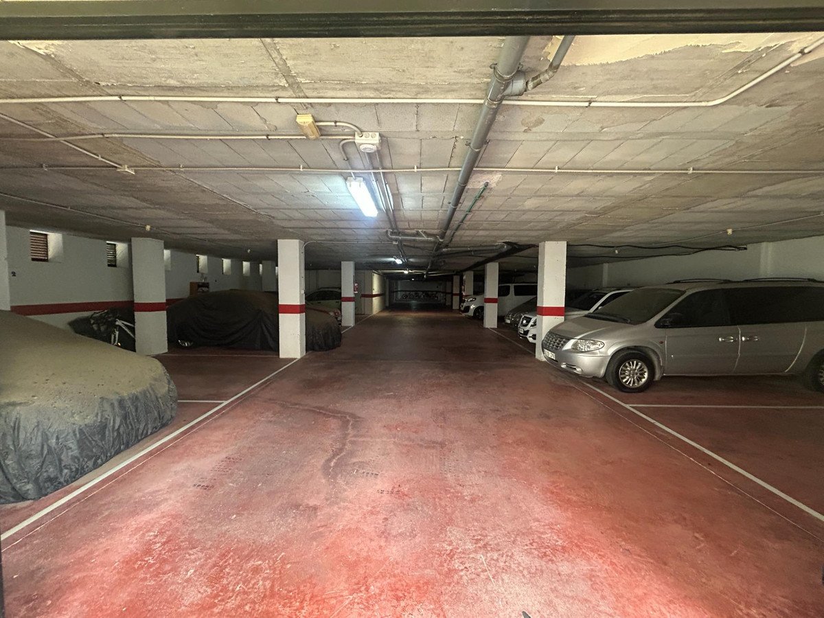 Underground parking garage with parked cars and concrete pillars