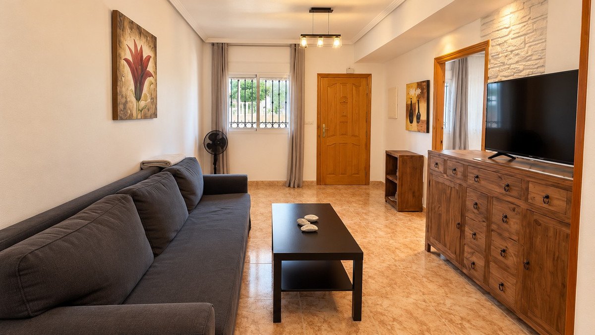 A modern living room with a large sofa, coffee table, and wooden TV console. Artwork adorns the walls.