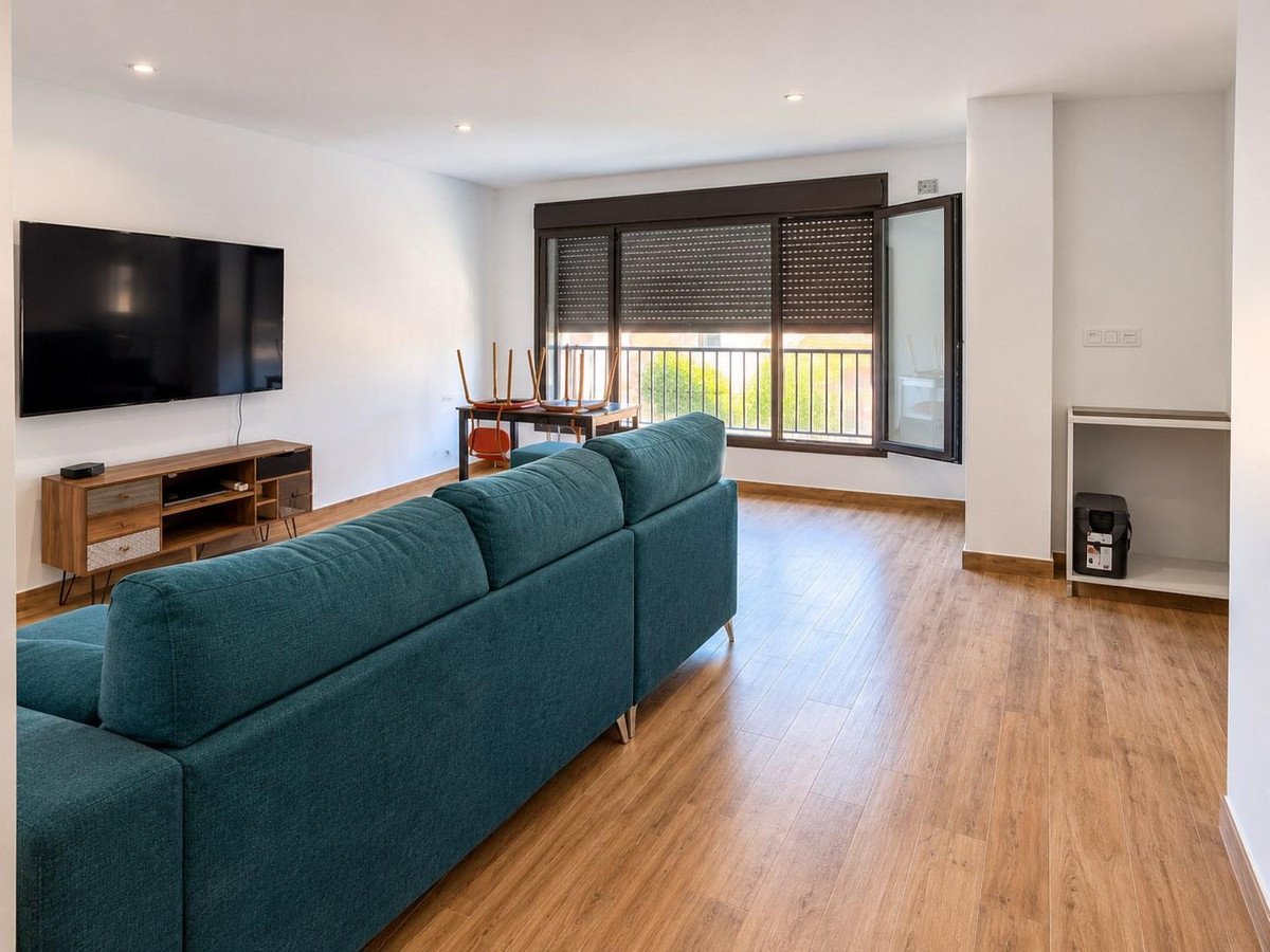 Living room with teal sofa, wooden flooring, and large window with outdoor view