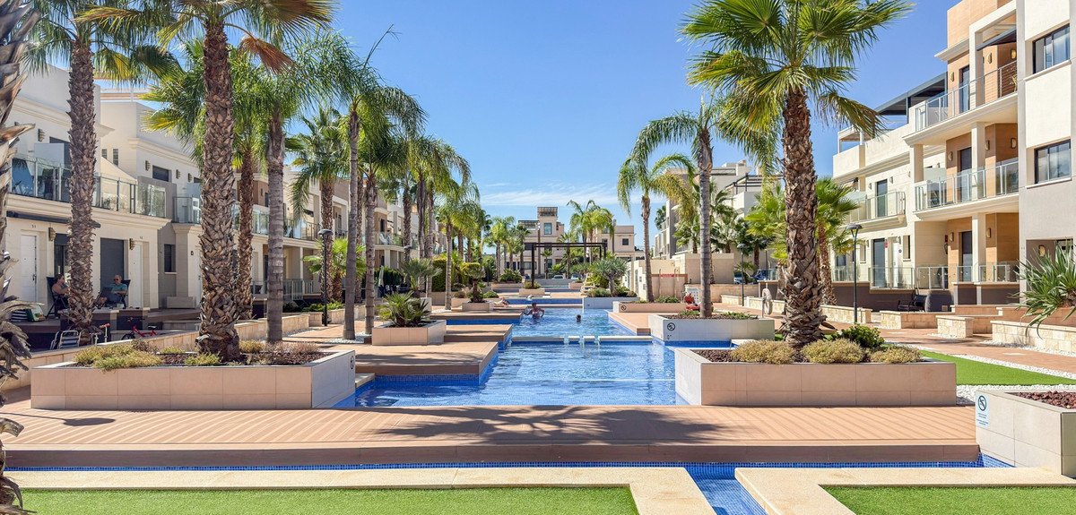 Resort-style pool with palm trees and modern condos in background
