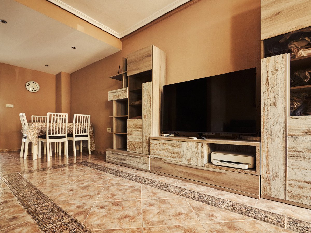 A living and dining room with a TV unit, dining table, and chairs.