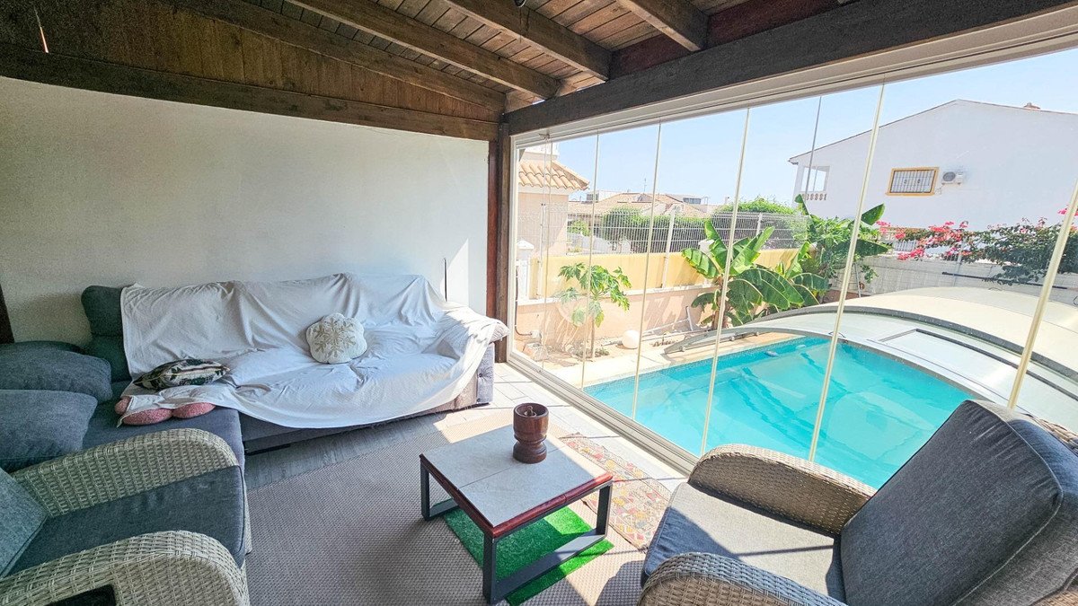 Covered patio with seating area overlooking swimming pool and outdoor space