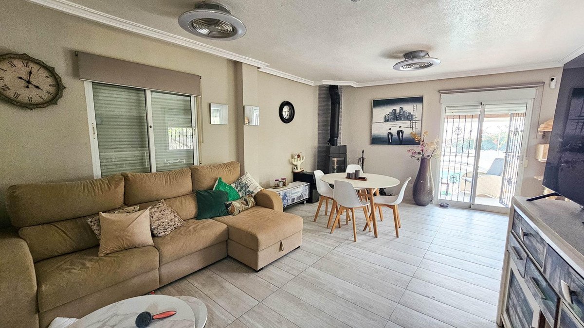 Living room with beige couch, dining table, and sliding glass doors to patio