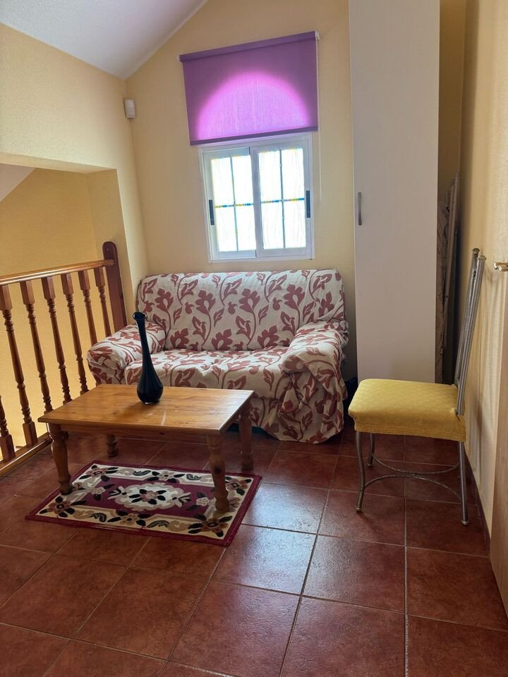 Cozy living room with floral sofa, wooden coffee table, and tiled floor