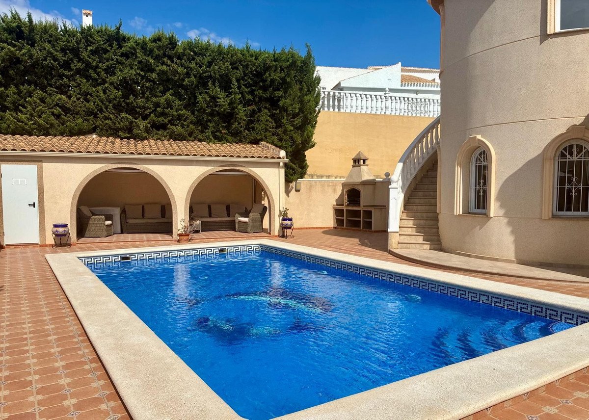 Villa outdoor area with swimming pool, patio, and arched seating under tiled roof