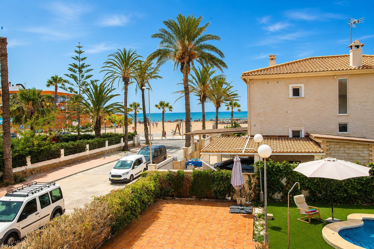 Villa with a swimming pool, garden, and a direct view of the beach and ocean, surrounded by palm trees.