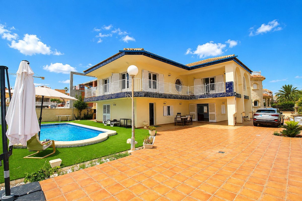 Spacious villa with a private swimming pool, tiled patio, and balcony, set against a bright blue sky.