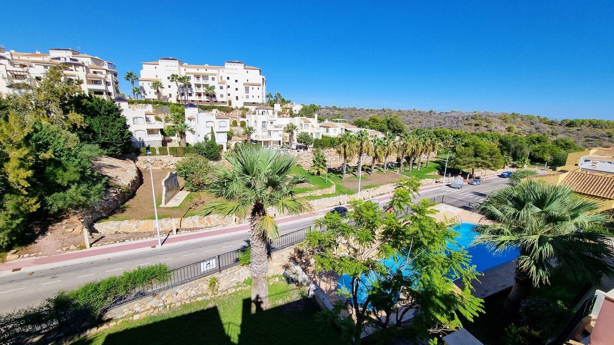 View of apartment buildings with palm trees and a blue swimming pool on a sunny day.
