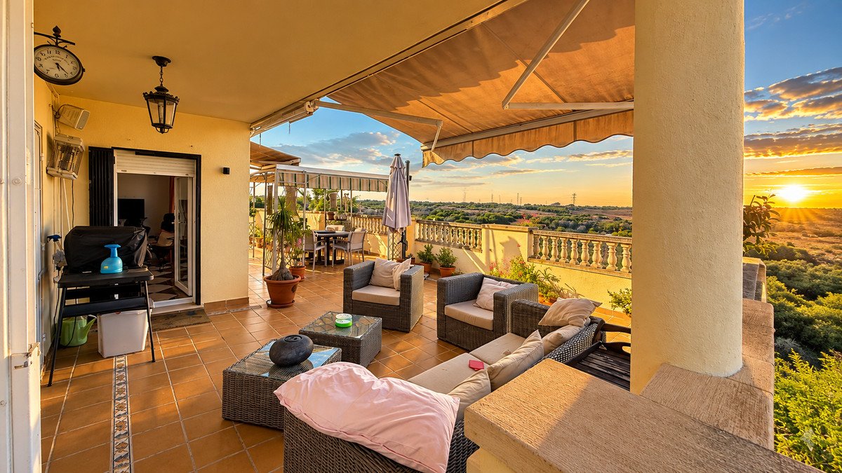 Spacious terrace with outdoor seating and a beautiful sunset view over the landscape. Includes a dining area and a barbecue grill.