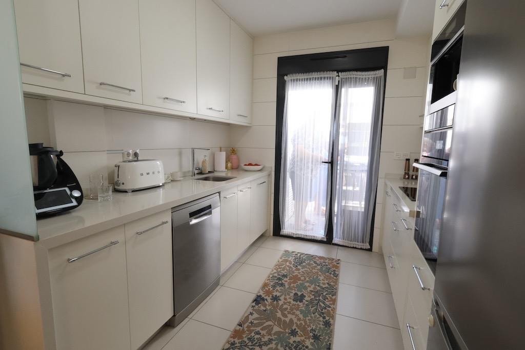 Modern white kitchen with double doors and stainless steel appliances