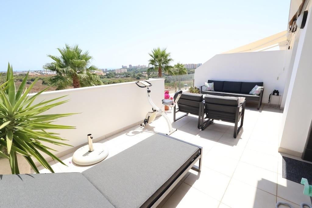 Balcony with sun lounger, sofa, and palm trees overlooking the city