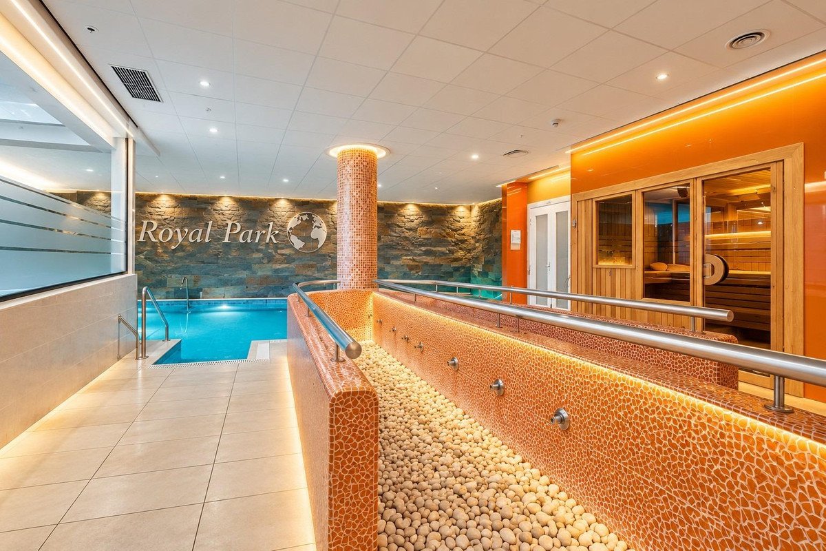 Indoor swimming pool with spa area, stone wall, and sauna in Royal Park building