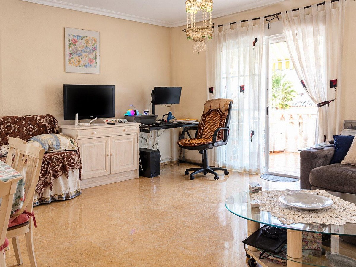 Spacious living room with glass coffee table, desk, and balcony view