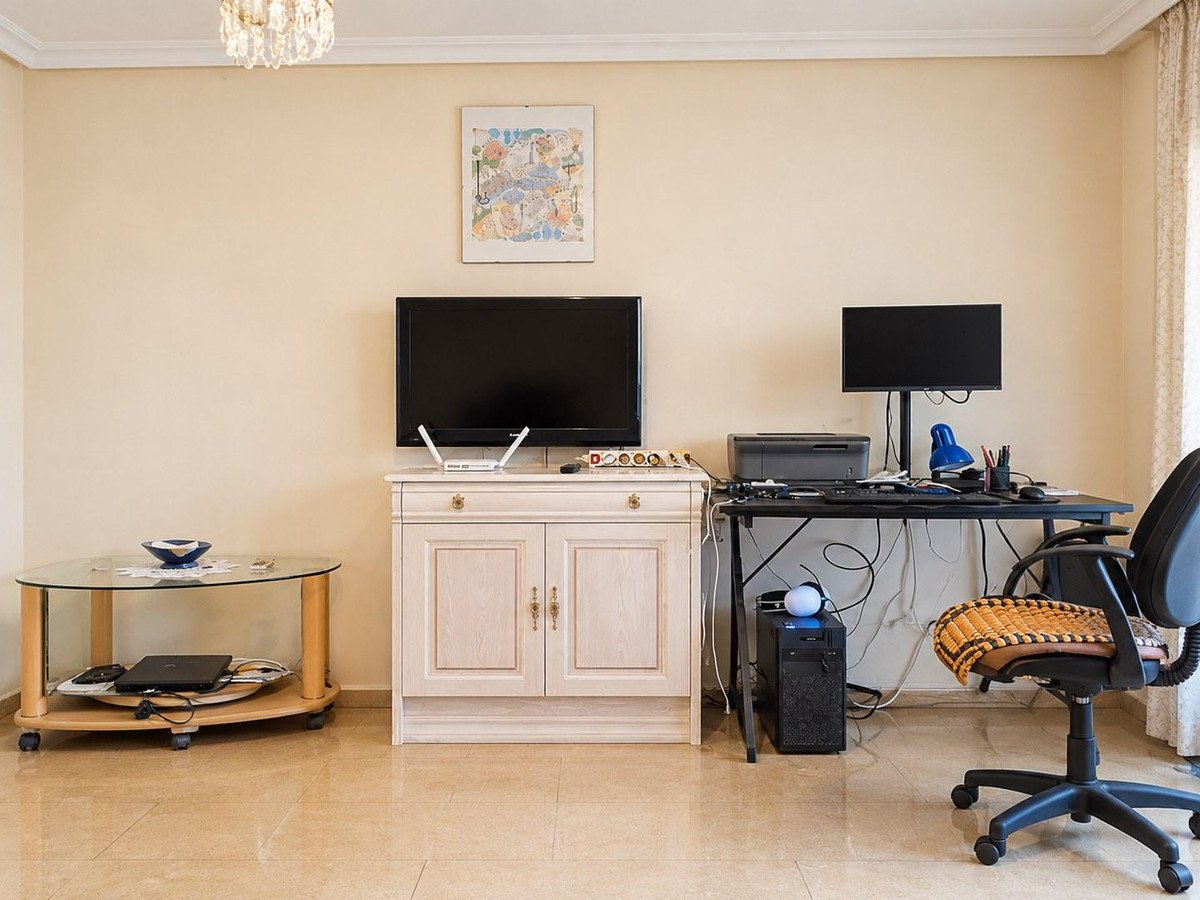 Living room with TV, desk, chair, and glass coffee table.