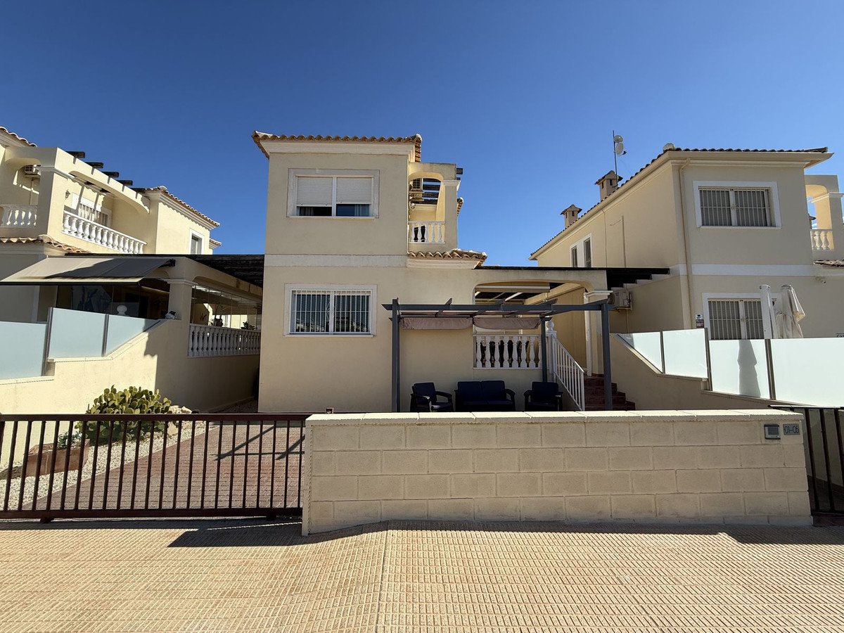 Exterior view of a modern townhouse with a terrace, outdoor seating area, and a secure gated entrance.