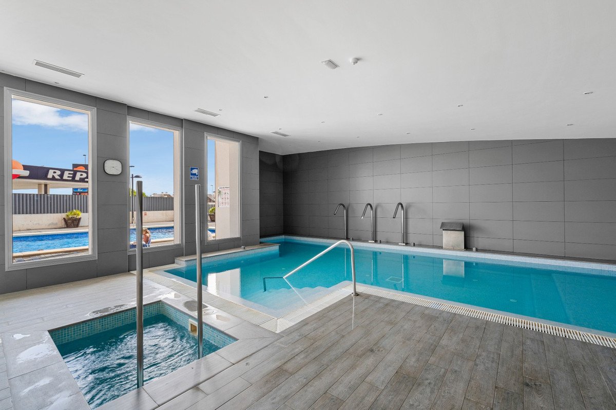 Indoor swimming pool with adjacent jacuzzi and large windows