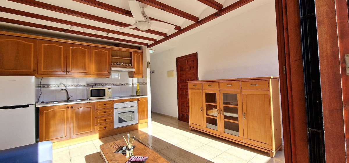 Open-plan kitchen and living room with wooden cabinets and tiled floor