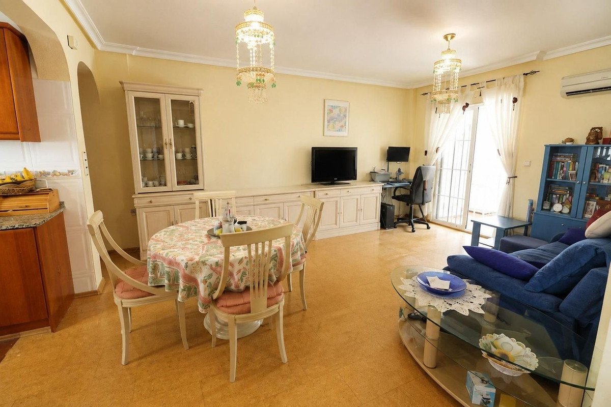 Living and dining area with a round table, blue sofa, desk, and a large cabinet with glass doors.