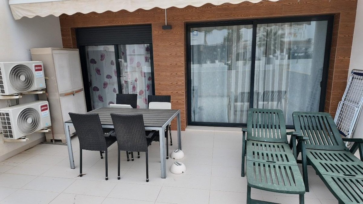 Outdoor patio with dining table, chairs, lounge chairs, and sliding glass doors