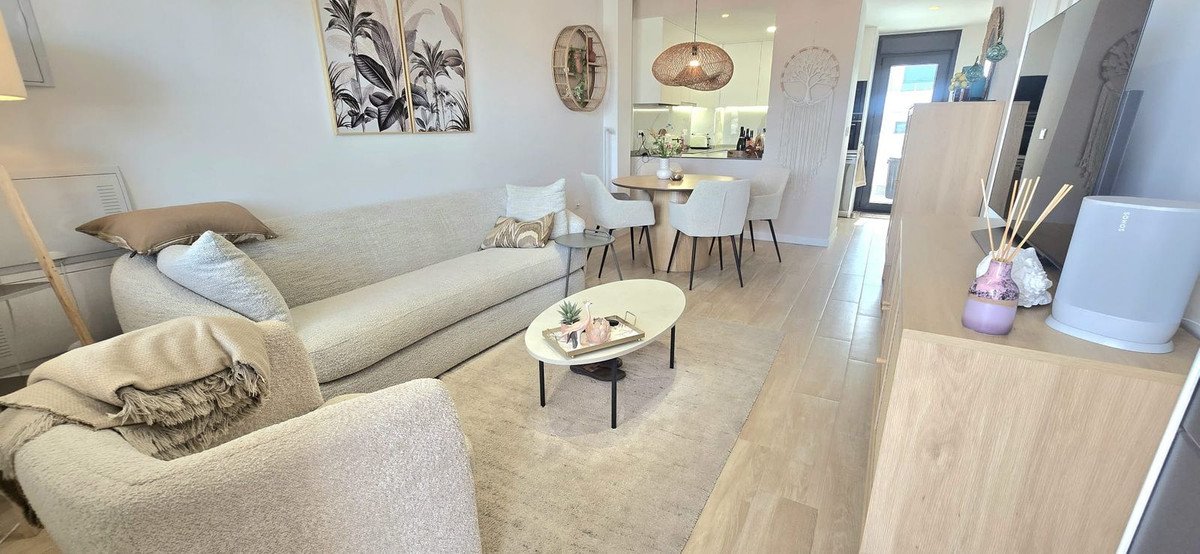 Modern living room with beige sofa, round table, and kitchen view.