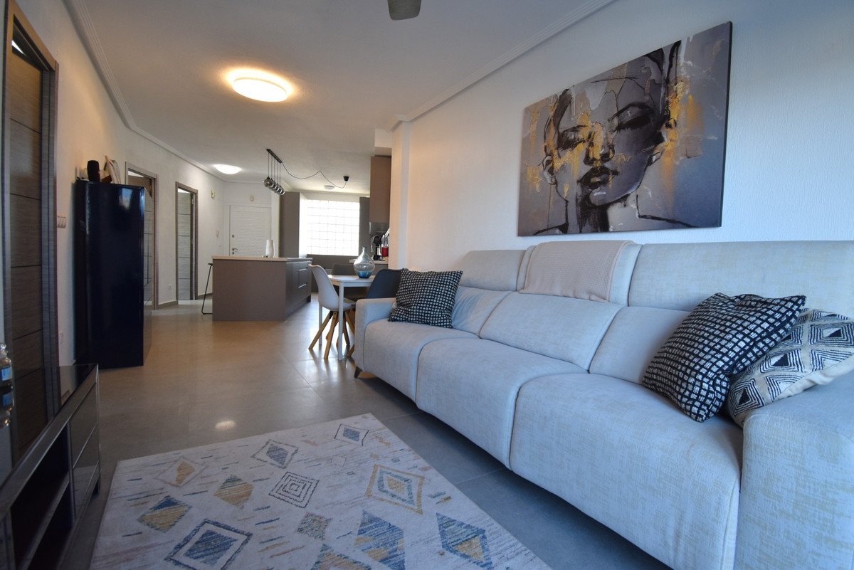 Open-concept living, dining, and kitchen area with a modern sofa, abstract art, and a central island.