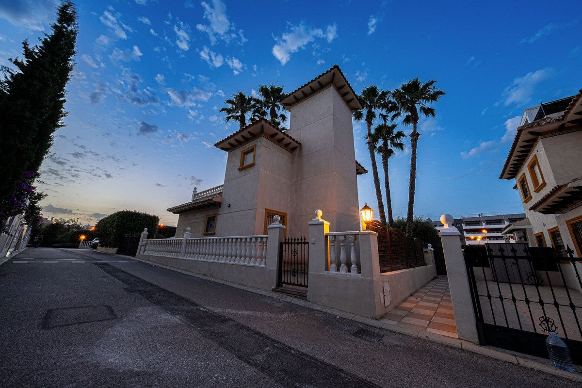 A detached villa with palm trees and balconies under a sunset sky.