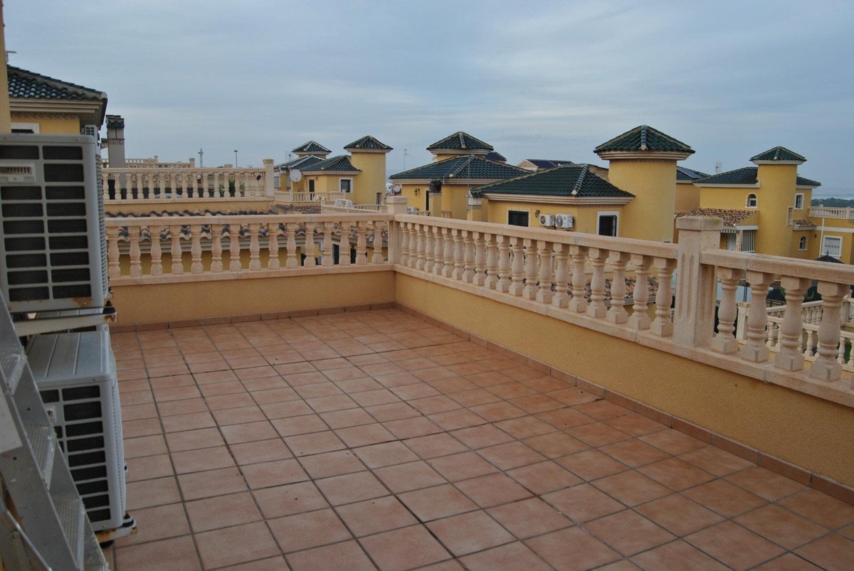 Rooftop terrace with tiled floor, balustrade, and view of yellow houses