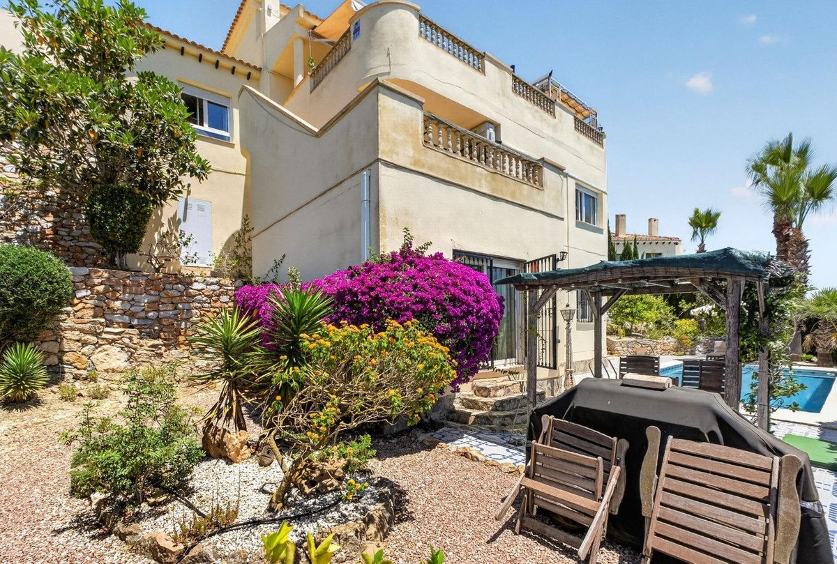 Villa with vibrant purple bougainvillea, a covered patio area with seating, and a glimpse of a swimming pool.