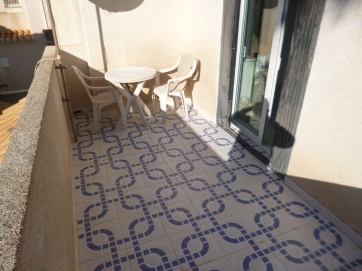 Balcony with white table and chairs on blue and white tiled floor