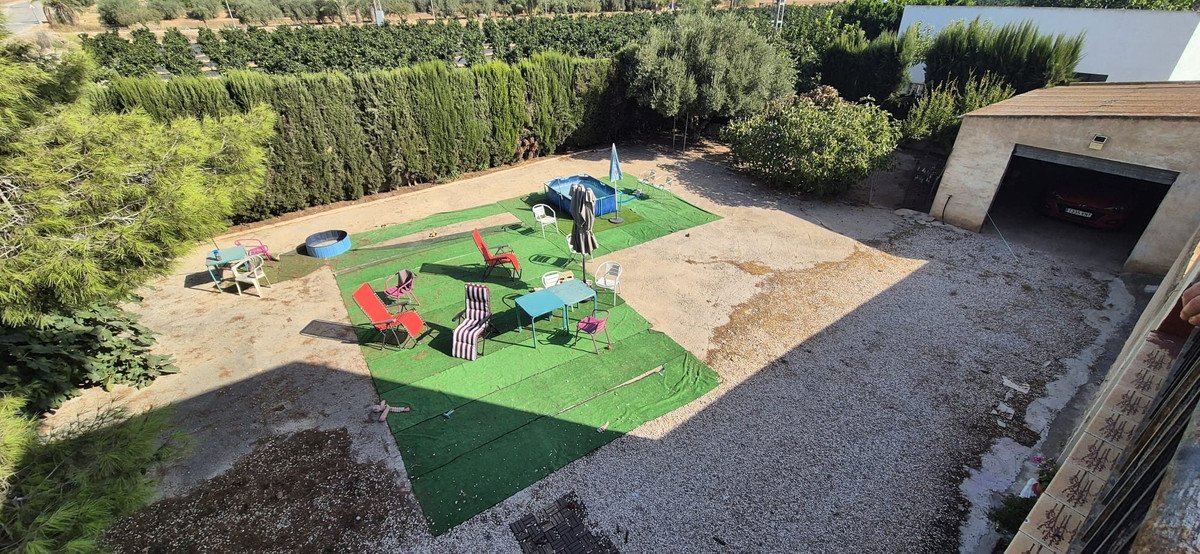 An outdoor area with a small inflatable pool, tables, chairs, and a garage with a car.