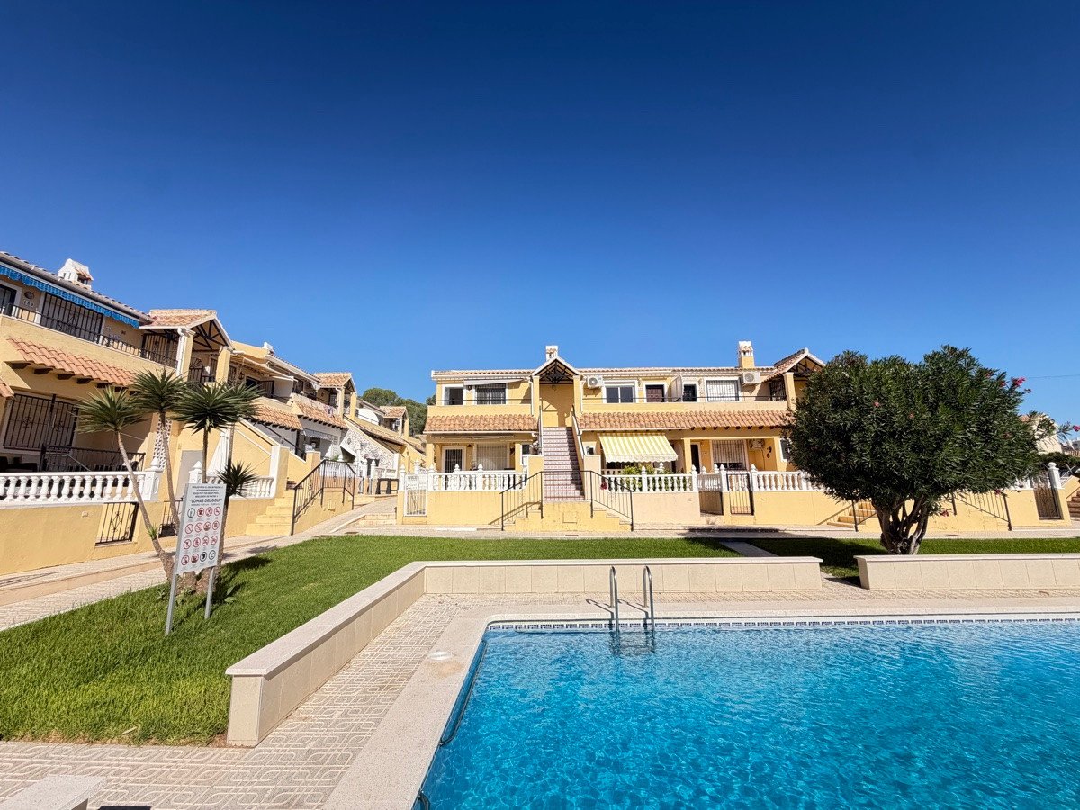 Yellow apartment complex with swimming pool and clear blue sky