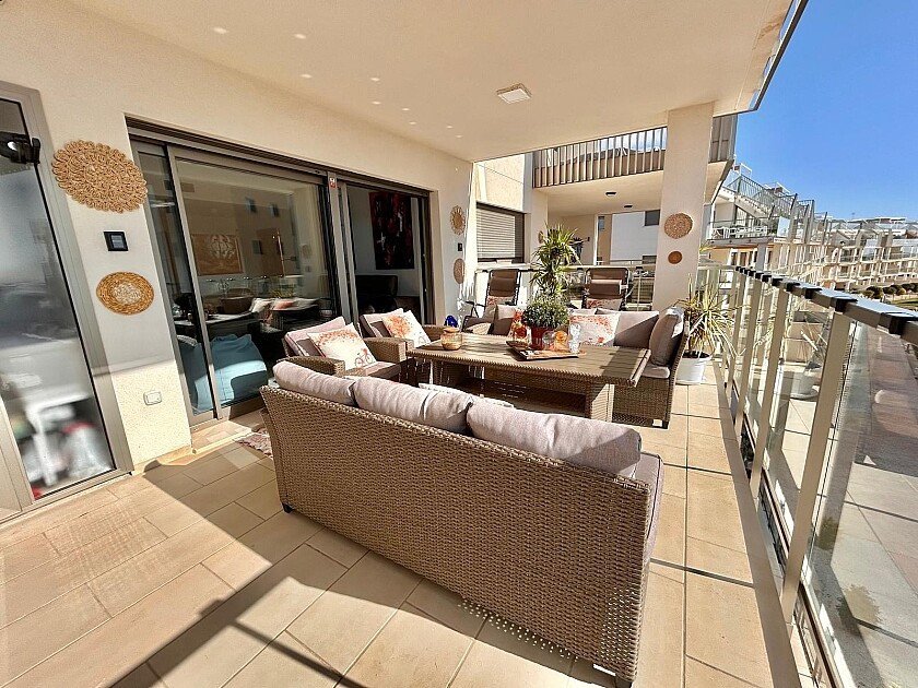 Spacious terrace with comfortable wicker furniture, dining set, and a beautiful view of the surrounding buildings and sky.