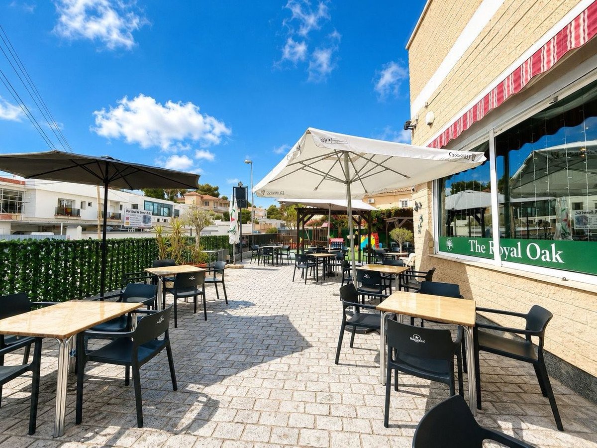 Outdoor patio with tables, chairs, umbrellas, and a view of a clear blue sky.
