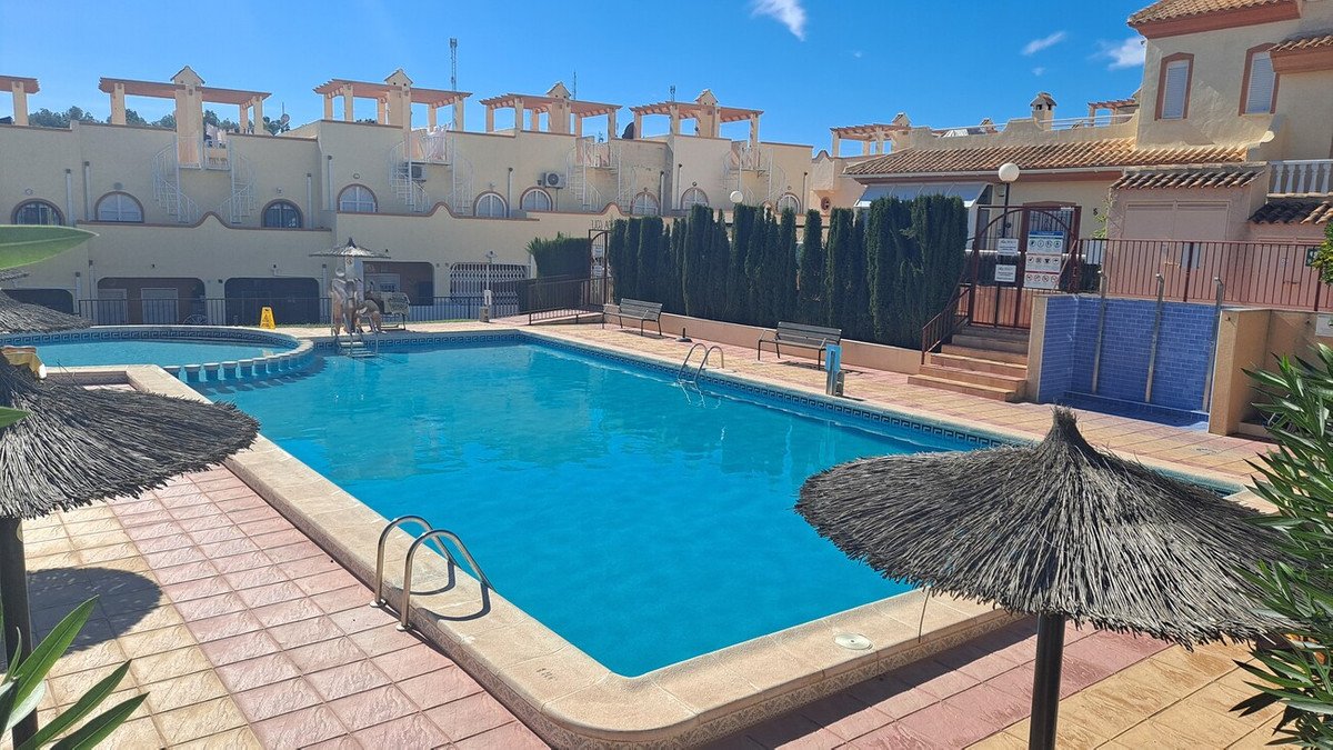 Resort swimming pool with sun shades and surrounding buildings