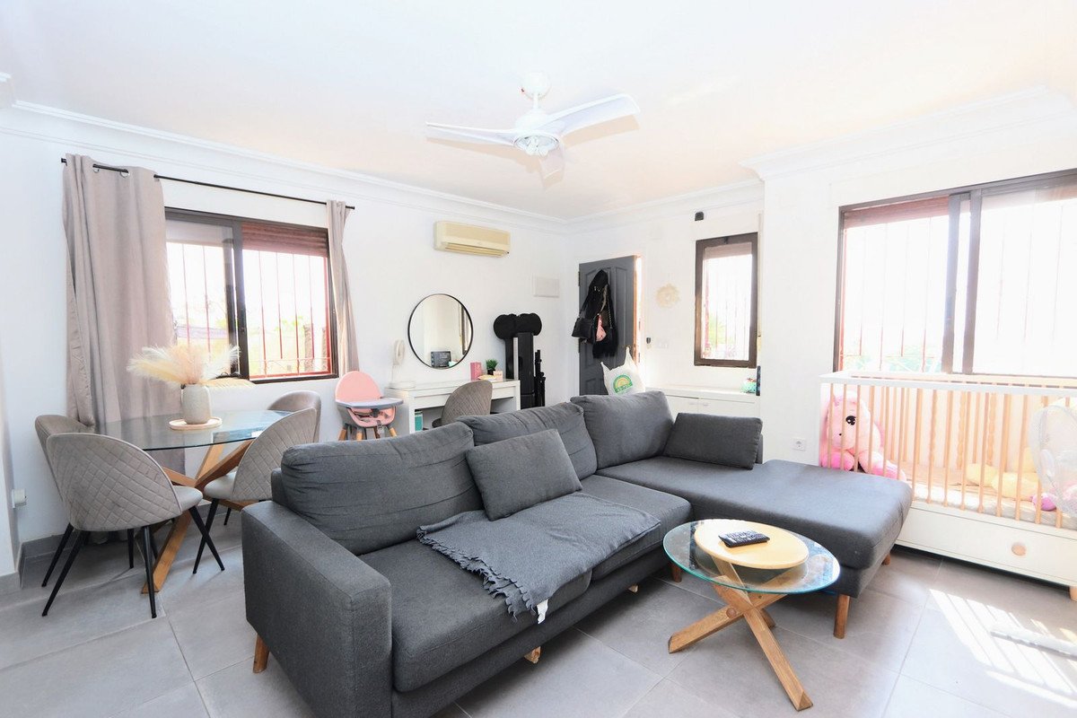 Spacious living and dining area with a large gray sectional sofa, glass dining table, and a crib with a stuffed toy.
