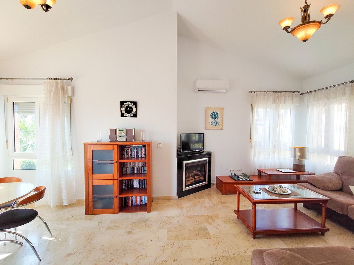 Spacious living room with a fireplace, TV, bookcase, coffee tables, and a dining area near the window.