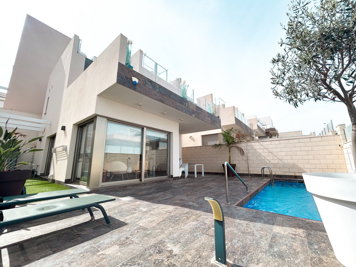 Modern villa exterior with a private swimming pool, sun loungers, and a terrace with large glass sliding doors.