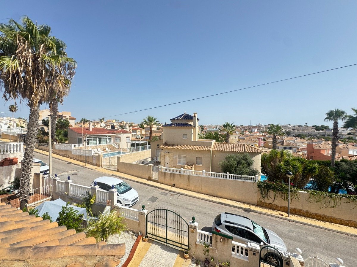 View of houses and a swimming pool with palm trees under a clear blue sky.