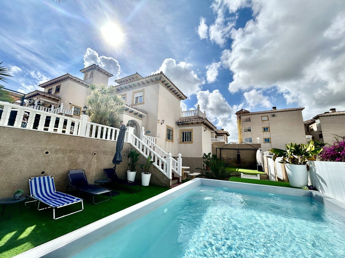Backyard of a villa with a swimming pool, sun loungers, and outdoor seating area