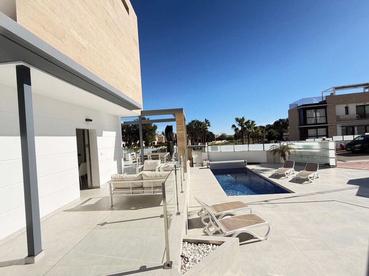 Modern villa with a private swimming pool, sun loungers, and a spacious terrace area on a sunny day.