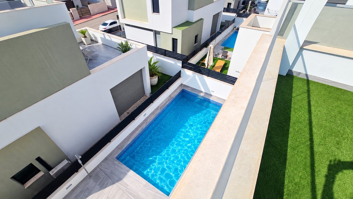 Aerial view of a modern villa with a private swimming pool, artificial turf, and outdoor seating areas.