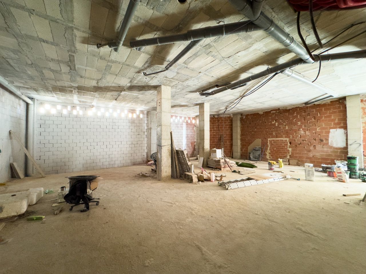 Onvoltooide kamer in een bouwplaats met bakstenen muren en betonnen plafonds.