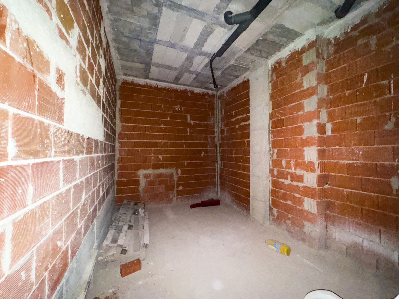 Onvoltooide kamer met bakstenen muren en betonnen plafond