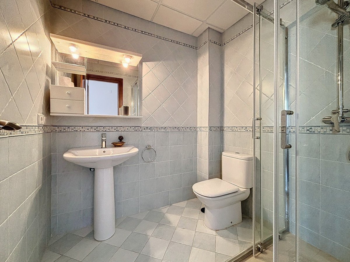 Badkamer met douchecabine, wastafel en toilet in lichte kleuren.