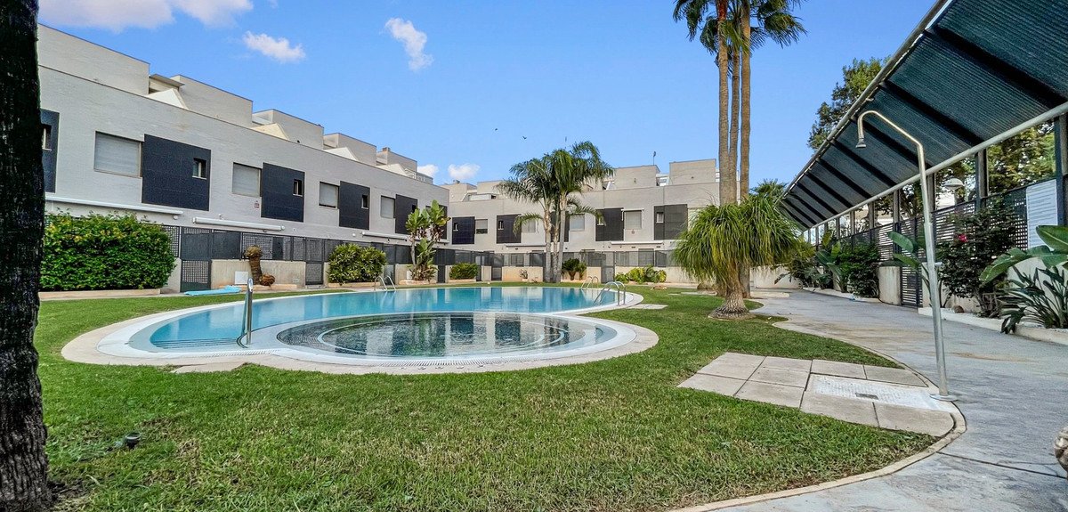 Modern townhouses surround a large, inviting swimming pool with a jacuzzi and outdoor shower area.