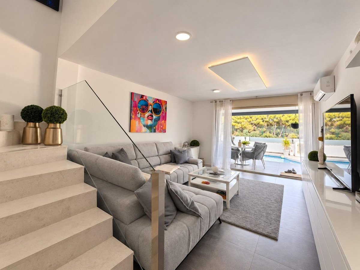 Modern living room with a large sectional sofa, coffee table, and a view of a private pool and outdoor dining area.