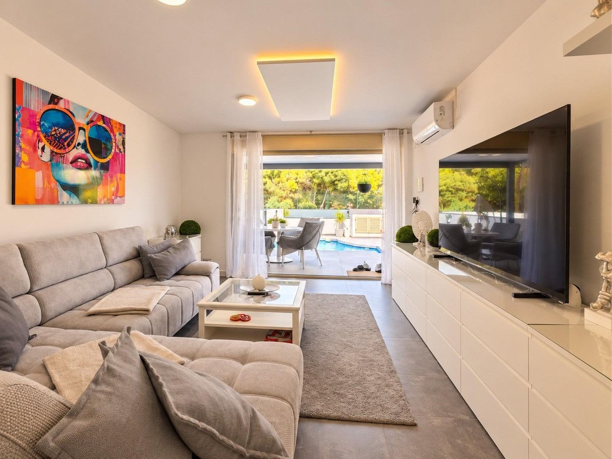 Modern living room with large sectional sofa, abstract art, and view of a swimming pool through glass doors.